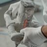 Close-up view of industrial worker's hands using a power mixer tool indoors.