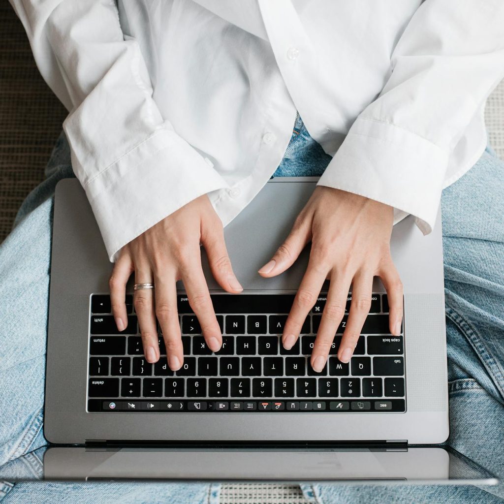 Hands of a person typing on a laptop while sitting on bed. Perfect for tech or lifestyle concepts.