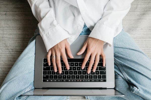Hands of a person typing on a laptop while sitting on bed. Perfect for tech or lifestyle concepts.